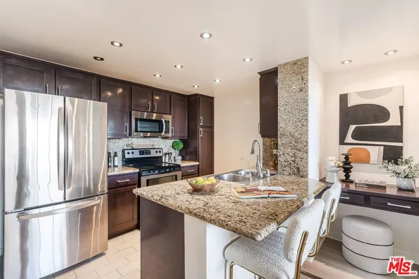 a kitchen with kitchen island granite countertop a sink stove and refrigerator