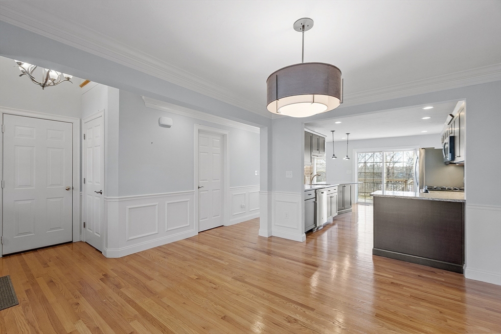 a view of empty room with wooden floor and kitchen view