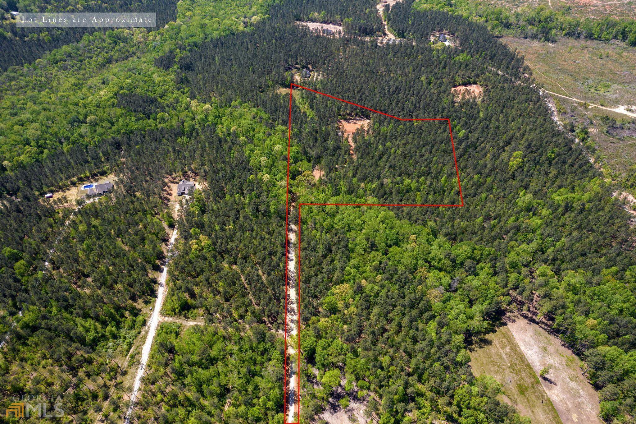 an aerial view of a house with a yard and covered with trees