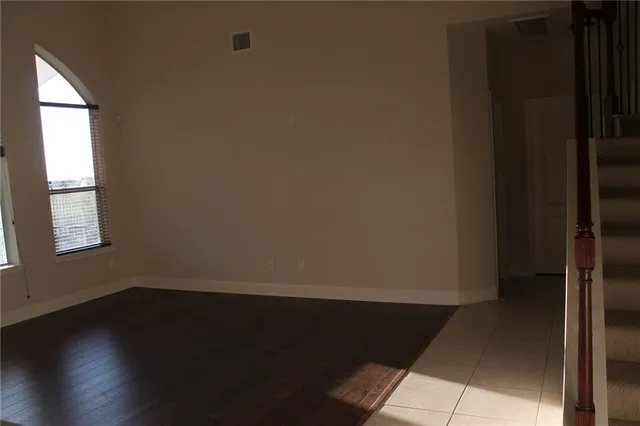 a view of an empty room with wooden floor and stairs