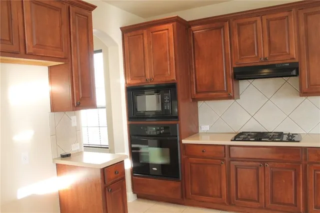 a kitchen with granite countertop wooden cabinets and a stove top oven