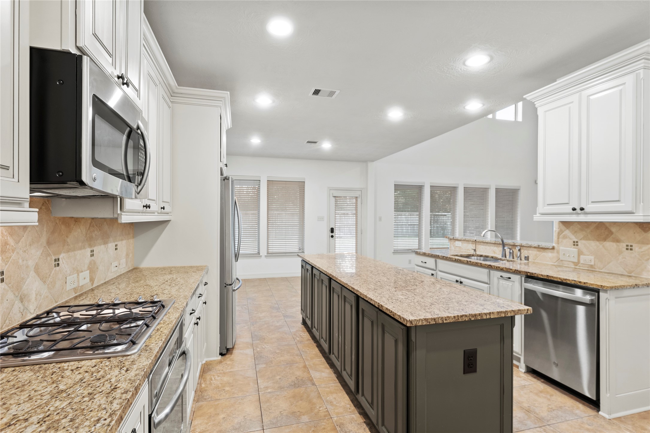 5827 Amherst Farms Lane Fulshear, TX 77441 - Photo 15 of 48 The final view emphasizes the spacious island and surrounding prep areas while offering a clear view toward the breakfast area and back windows. Abundant recessed lighting and neutral finishes create a bright, cohesive design that flows effortlessly into the adjoining living spaces.