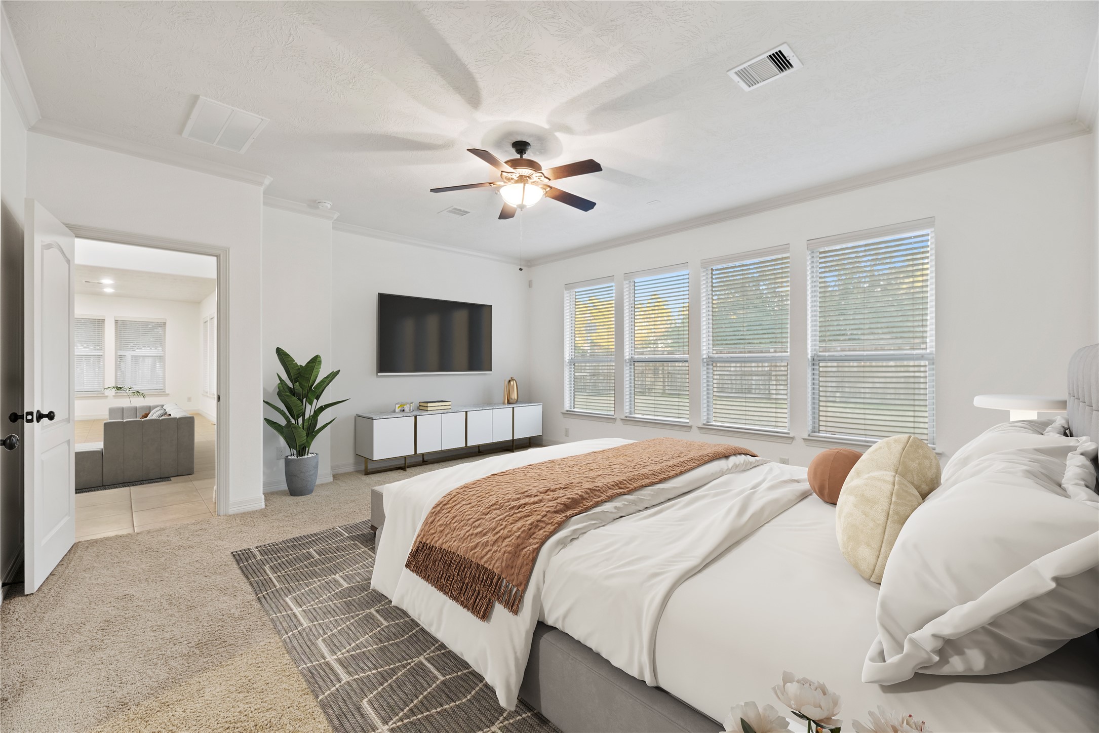 5827 Amherst Farms Lane Fulshear, TX 77441 - Photo 17 of 48 The spacious primary suite offers a peaceful retreat with plush carpet, soft neutral tones, & elegant crown molding. A tray ceiling adds dimension, while the ceiling fan with light fixture provides comfort year-round. A wall of large windows fills the space with natural light. This virtually staged view highlights the impressive scale.