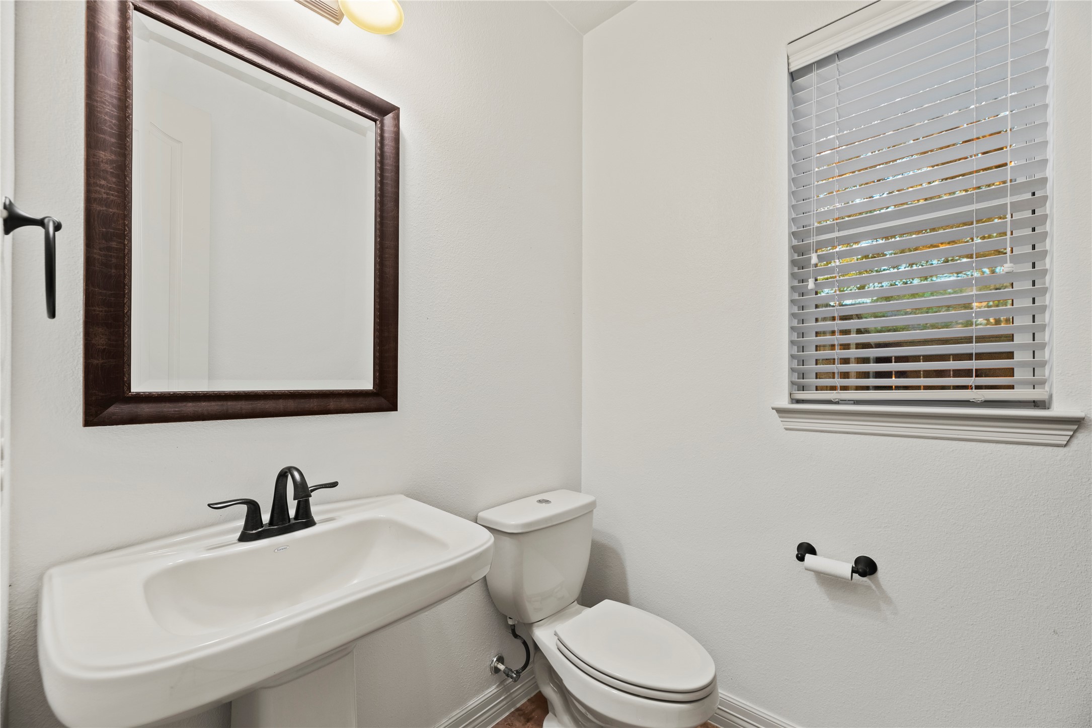 5827 Amherst Farms Lane Fulshear, TX 77441 - Photo 21 of 48 The conveniently located powder bath features a pedestal sink with an oil-rubbed bronze faucet, coordinating hardware, and a framed mirror for a polished look.