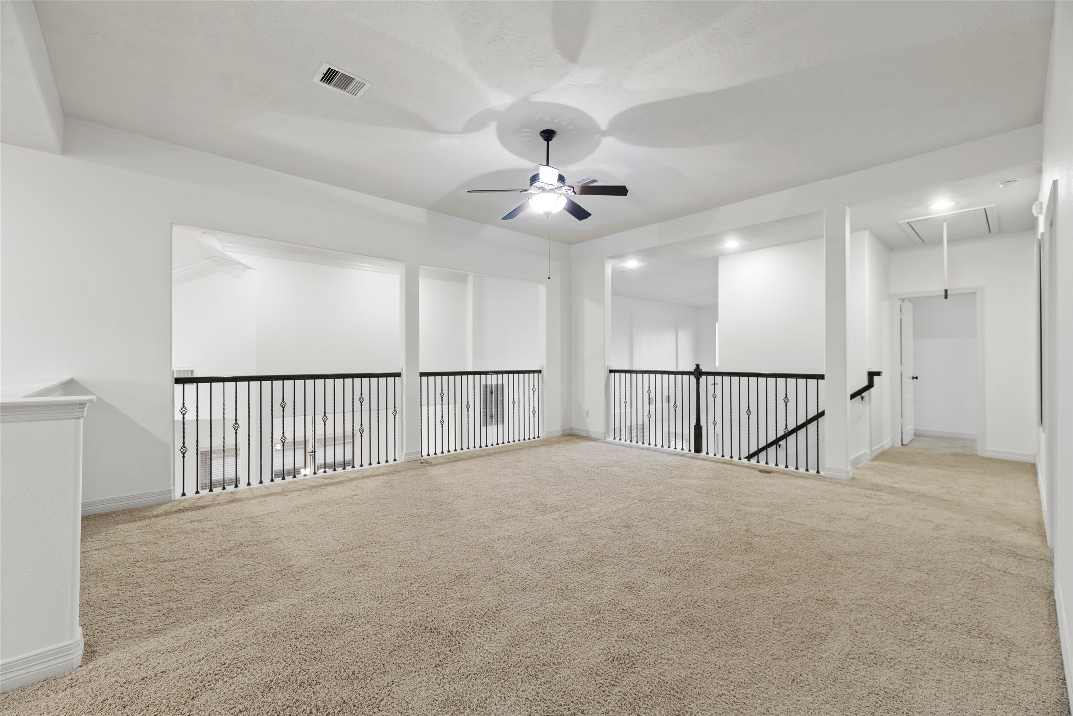 5827 Amherst Farms Lane Fulshear, TX 77441 - Photo 23 of 48 The oversized upstairs game room offers exceptional flexibility with an open layout overlooking the two-story foyer below. Wrought-iron balusters add architectural charm while maintaining open sightlines. Plush carpeting, recessed lighting, and a ceiling fan create a comfortable environment perfect for a media room, playroom, or additional living space.