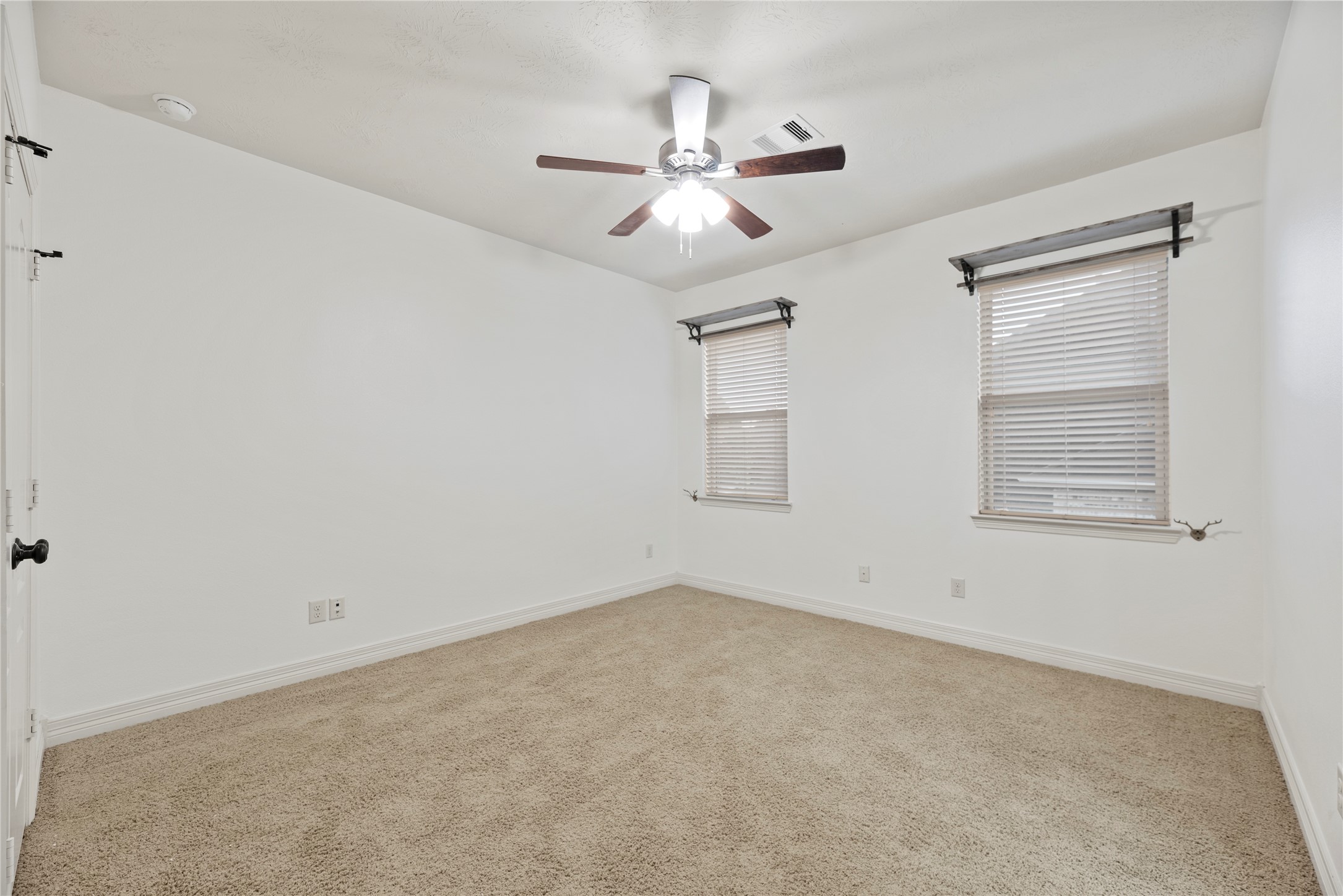 5827 Amherst Farms Lane Fulshear, TX 77441 - Photo 29 of 48 Another spacious bedroom offers two windows that fill the space with natural light. Decorative curtain rods add character, while the neutral color palette allows for versatile styling. Plush carpeting and a ceiling fan complete this inviting space.