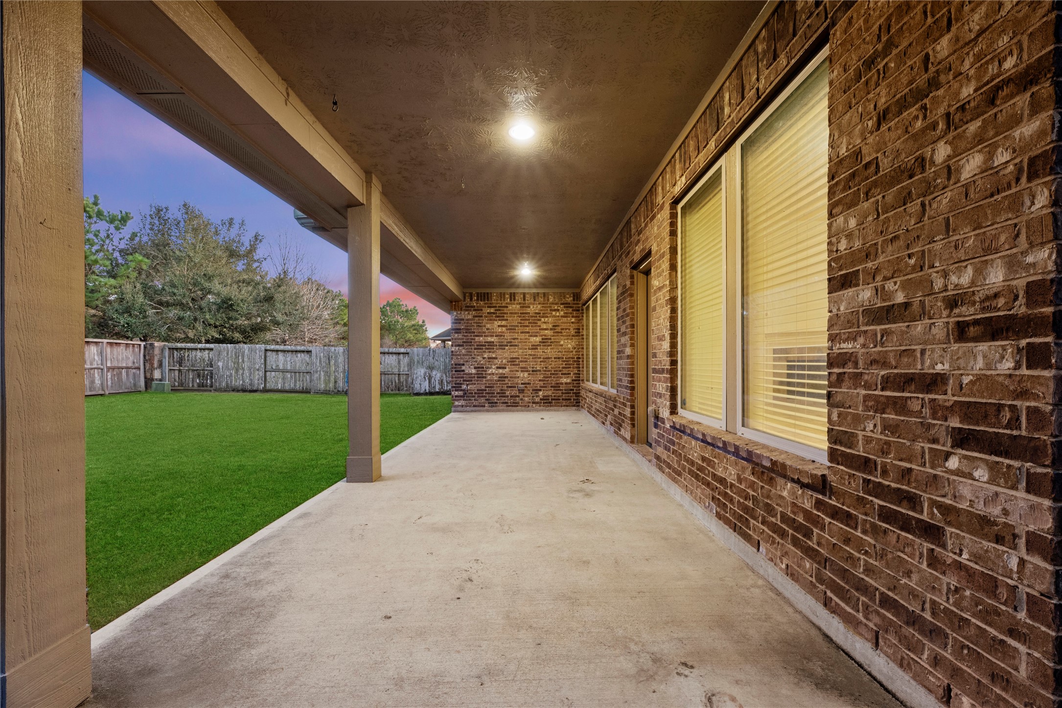 5827 Amherst Farms Lane Fulshear, TX 77441 - Photo 34 of 48 This side-angle view captures the length of the covered patio and the expansive backyard beyond. The covered area offers shade during the day and a cozy, well-lit setting in the evening.