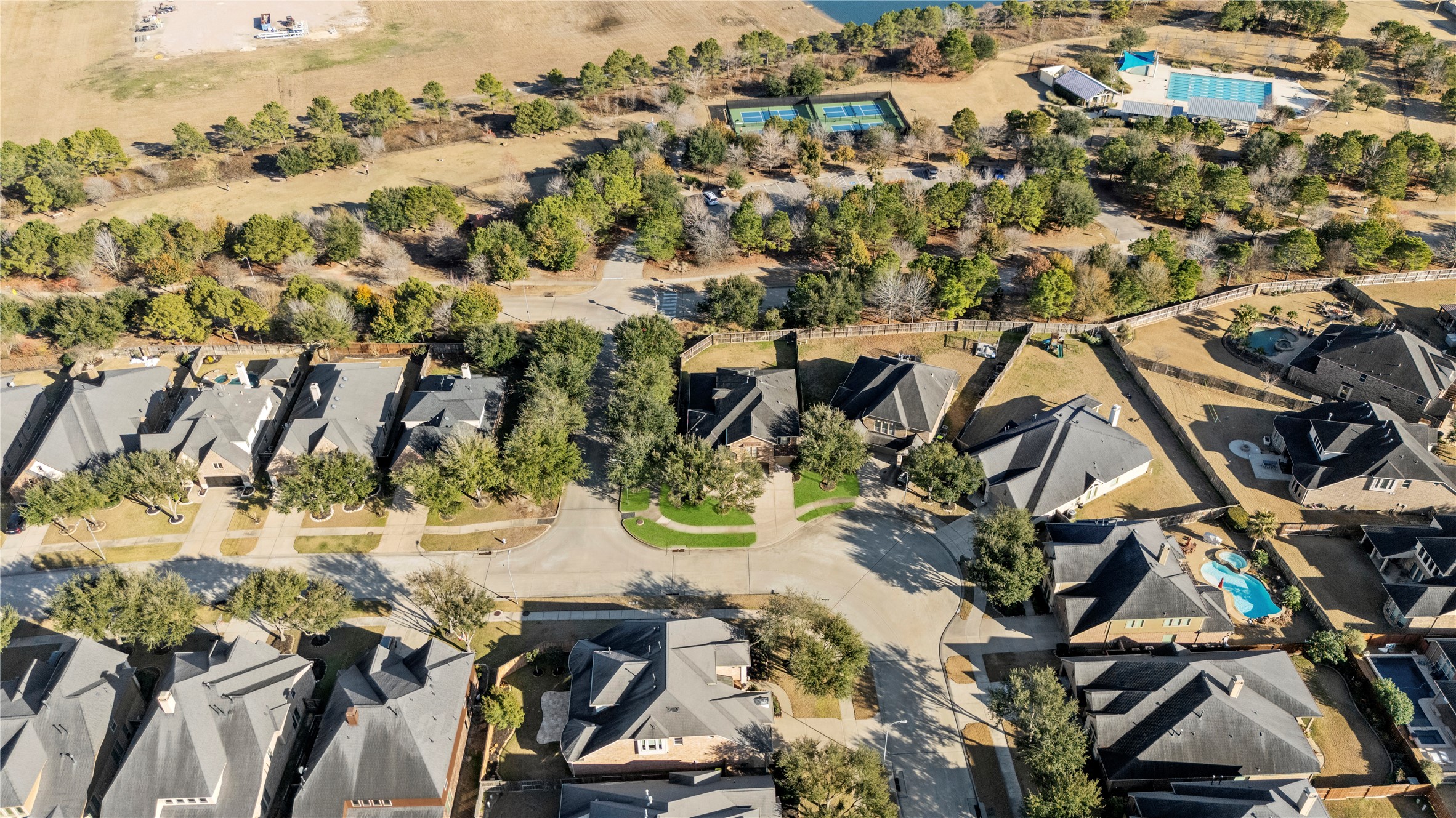 5827 Amherst Farms Lane Fulshear, TX 77441 - Photo 38 of 48 Elevated neighborhood view captures the home’s desirable setting with greenbelt trails, sport courts, and community pool amenities just moments away. The surrounding mature trees create a peaceful, park-like environment.