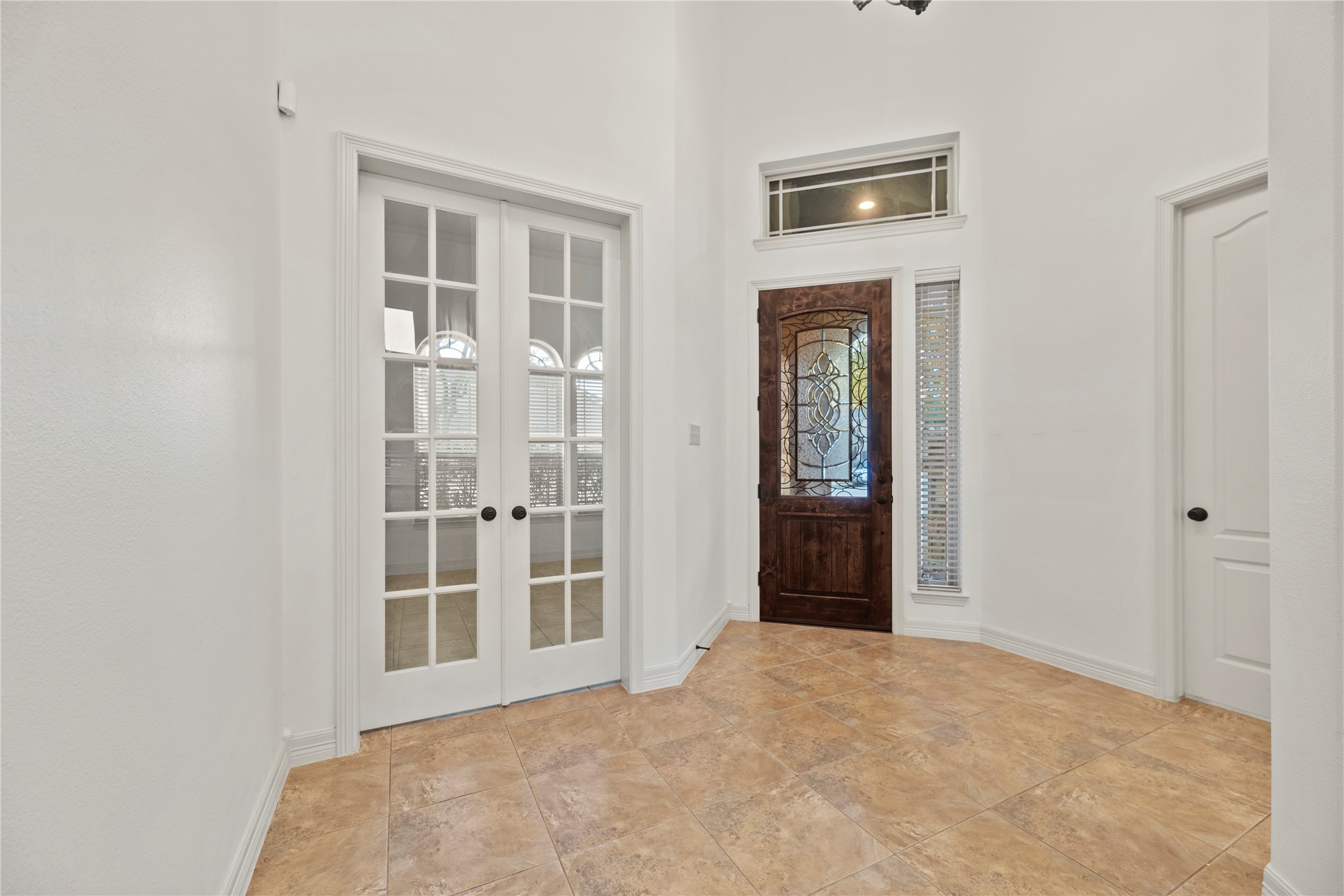 5827 Amherst Farms Lane Fulshear, TX 77441 - Photo 4 of 48 This angle highlights the spacious foyer and the beautifully positioned glass-paneled French doors leading to a private study. The tall ceilings and clean lines provide a bright, airy aesthetic, while the neutral tile flooring flows seamlessly into the main living areas.