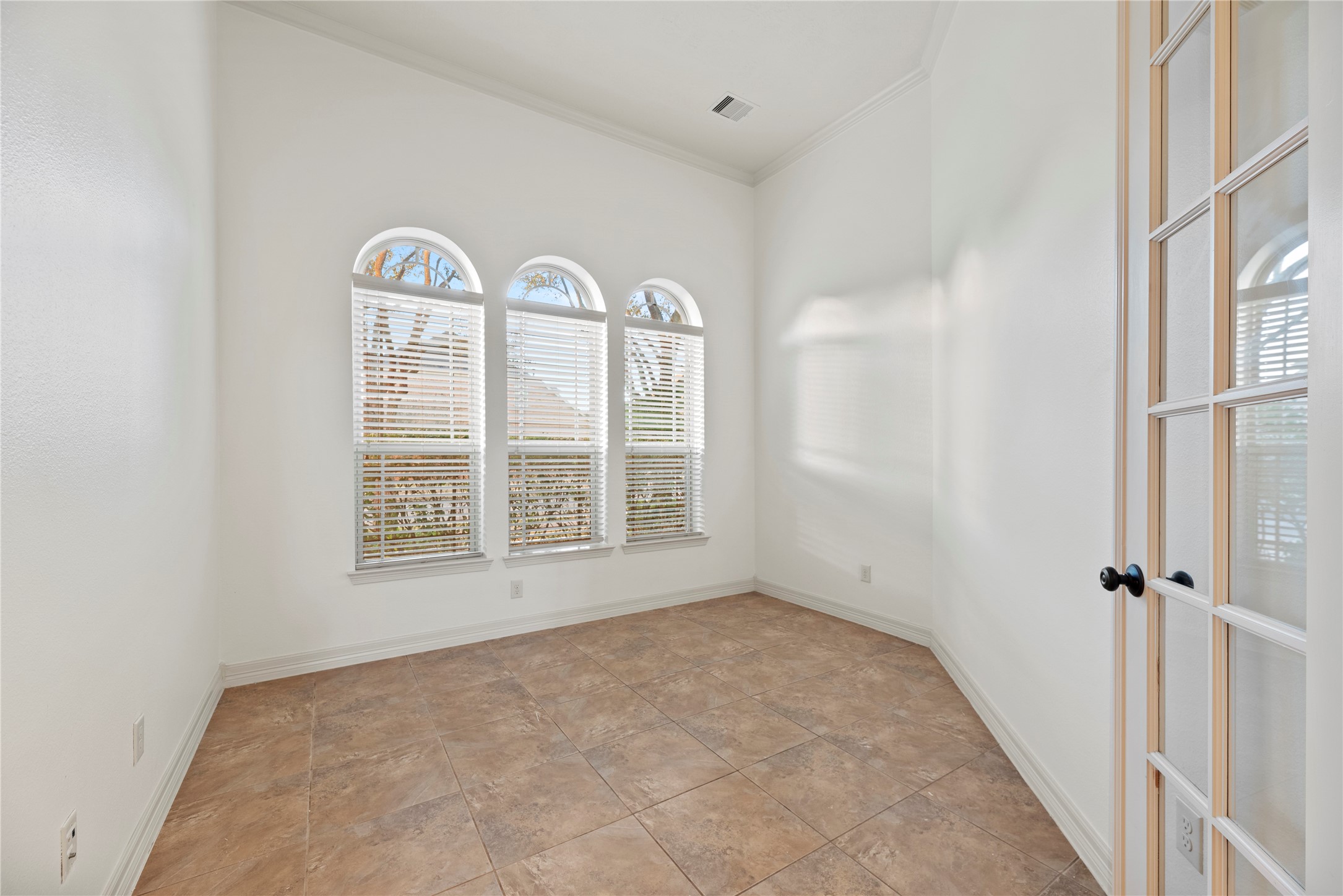 5827 Amherst Farms Lane Fulshear, TX 77441 - Photo 5 of 48 The dedicated study offers a serene and light-filled workspace featuring three charming arched windows that allow abundant natural light to stream in. High ceilings and neutral tones enhance the sense of space, while the tile flooring ensures durability and easy maintenance.