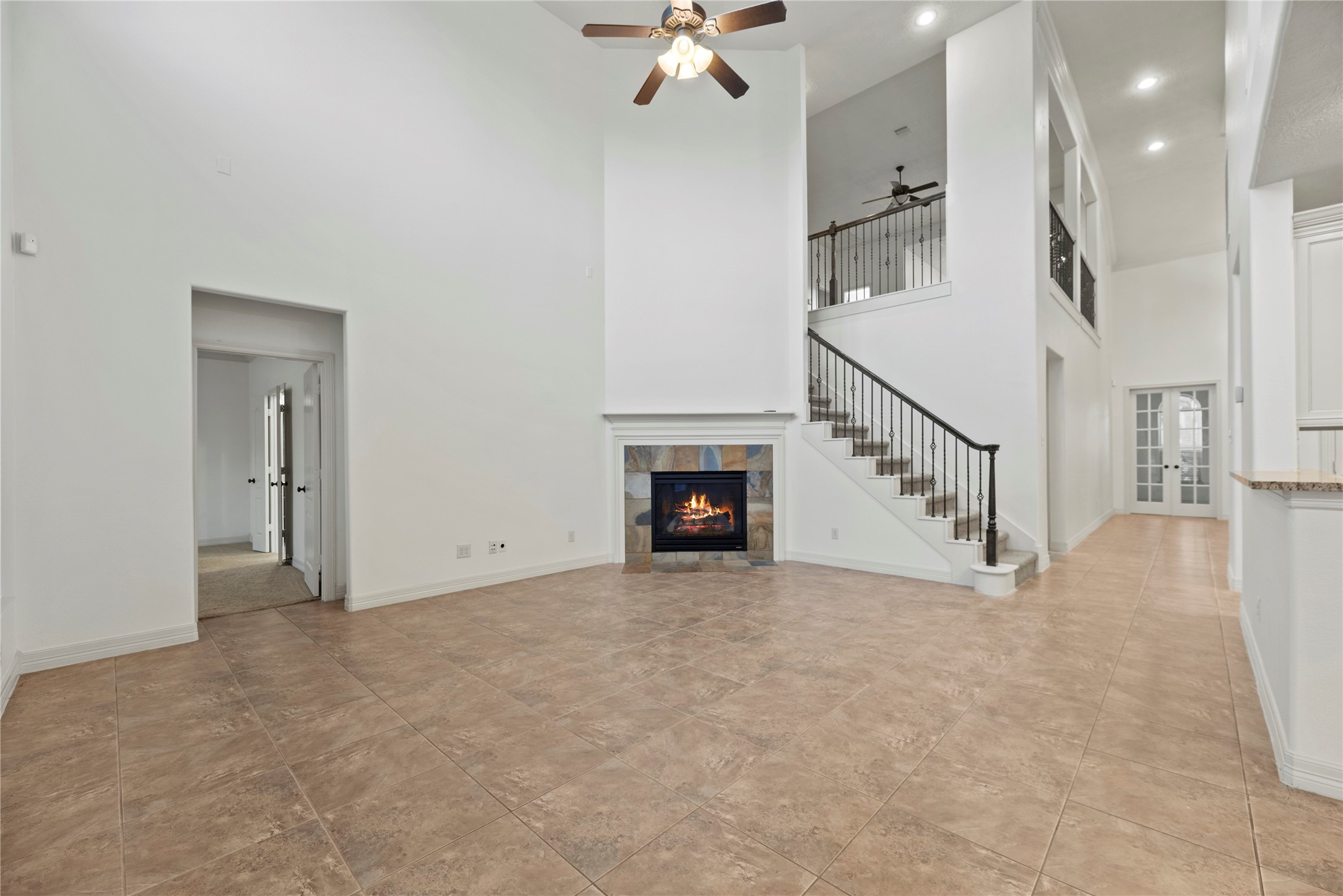 5827 Amherst Farms Lane Fulshear, TX 77441 - Photo 10 of 48 From this vantage point, the fireplace remains a central focal feature, framed by soaring white walls and enhanced by the staircase that leads to the second-floor game room and bedrooms. The open railing above overlooks the living space below, reinforcing the home’s airy two-story design and allowing natural light to circulate throughout.