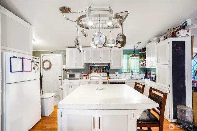 a kitchen with a refrigerator a stove top oven a clock and a view of kitchen