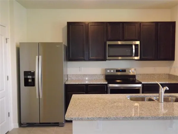 a kitchen with granite countertop a refrigerator and a stove top oven