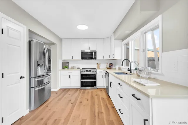 a large kitchen with cabinets wooden floor and stainless steel appliances
