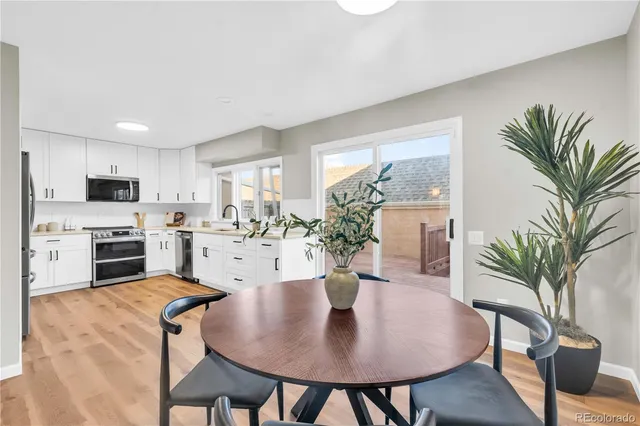 a living room with furniture potted plant and kitchen view