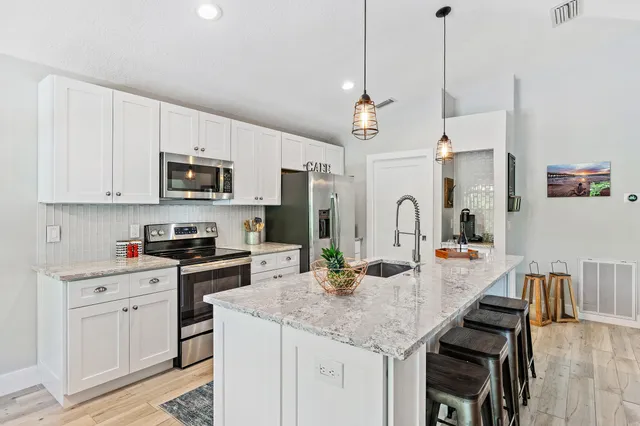 a kitchen with kitchen island granite countertop a stove a sink a center island and cabinets