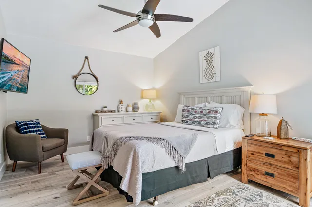 a bedroom with a bed a desk and chair with wooden floor