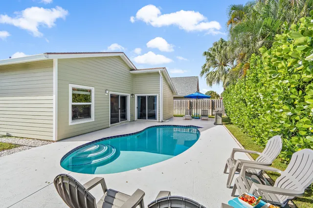 a view of a house with pool fire pit and chairs in the patio