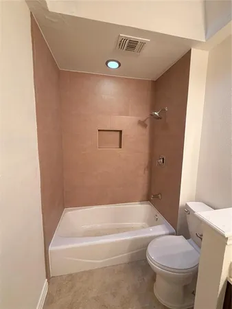 a bathroom with a granite countertop toilet and a bathtub