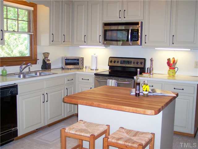 9321 Foxburrow Court Raleigh, NC 27613 - Photo 2 of 12 a kitchen with stainless steel appliances a stove a sink and white cabinets