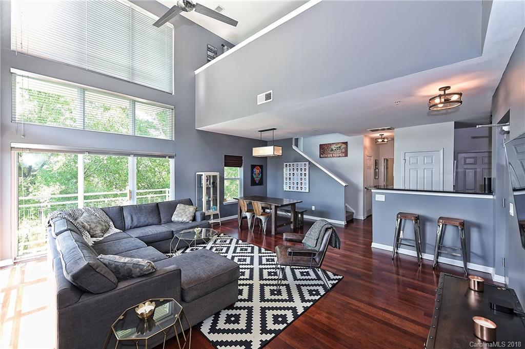 a living room with furniture two window and wooden floor
