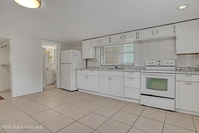 a view of a house with a yard plants and large tree