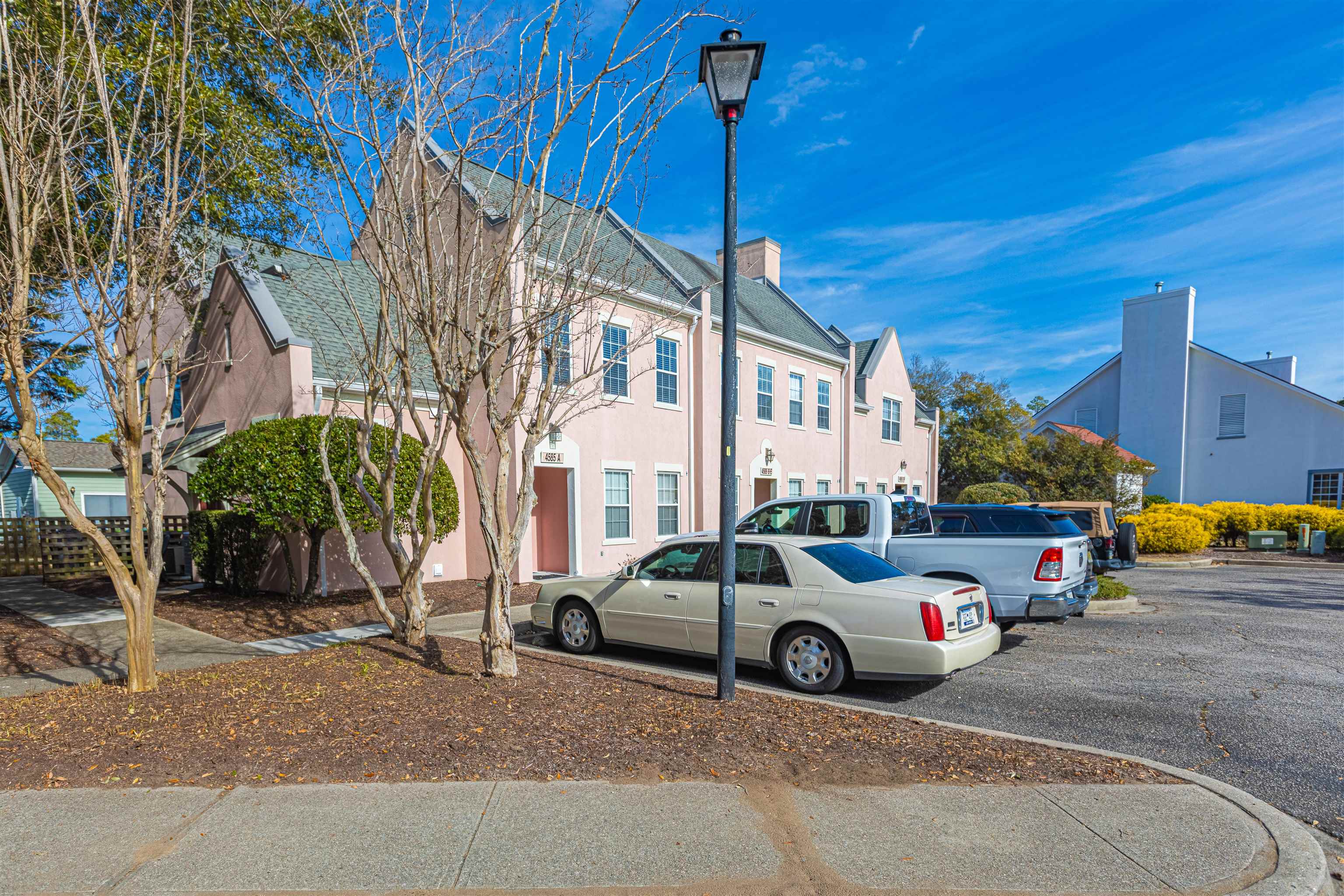 4585 Girvan Drive, Unit D Myrtle Beach, SC 29579 - Photo 3 of 32 View of front facade featuring a chimney, stucco siding, uncovered parking, and a residential view