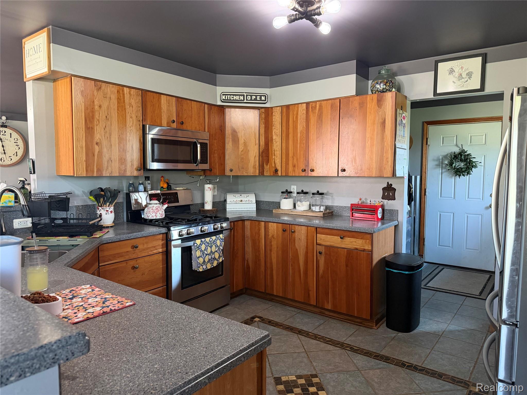6860 Grand River Road Bancroft, MI 48414 - Photo 7 of 31 Kitchen with wood finish cabinets, stainless steel appliances, and inlaid floor details