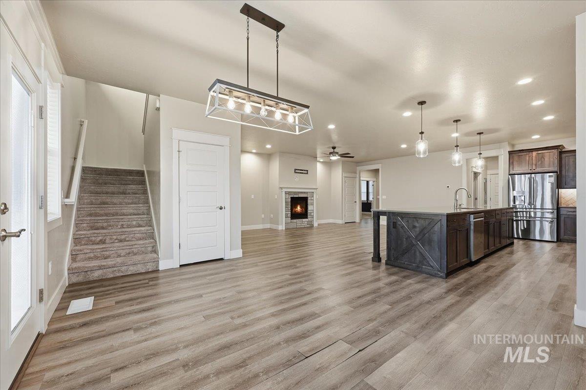 92 South Ravine Way Nampa, ID 83687 - Photo 29 of 29 Kitchen with open floor plan, a fireplace, a center island with sink, appliances with stainless steel finishes, and dark brown cabinets