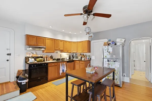 a kitchen with stainless steel appliances kitchen island granite countertop a table chairs in it and wooden floors