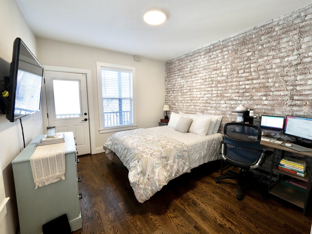 65 Border Street, Unit 4 Boston, MA 02128 - Photo 8 of 15 a bedroom with a bed next to a window with wooden floor