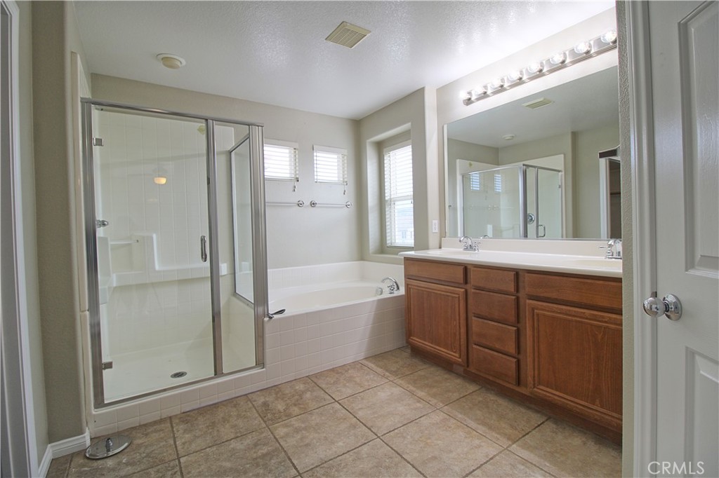 1637 Rigel Street Beaumont, CA 92223 - Photo 15 of 22 a bathroom with a tub a sink and mirrors