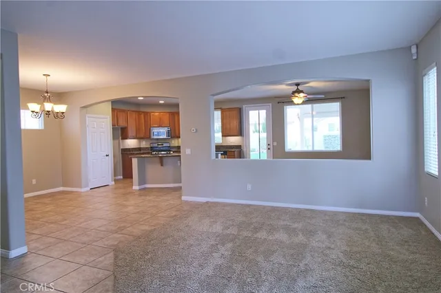an empty room with kitchen view and windows