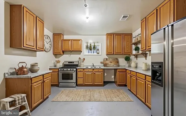 a kitchen with stainless steel appliances granite countertop a stove top oven a sink dishwasher a refrigerator and cabinets with wooden floor