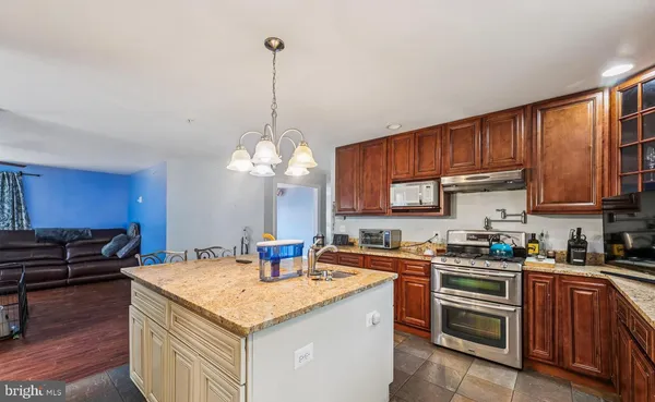 a kitchen with stainless steel appliances granite countertop a sink a stove and a wooden floors