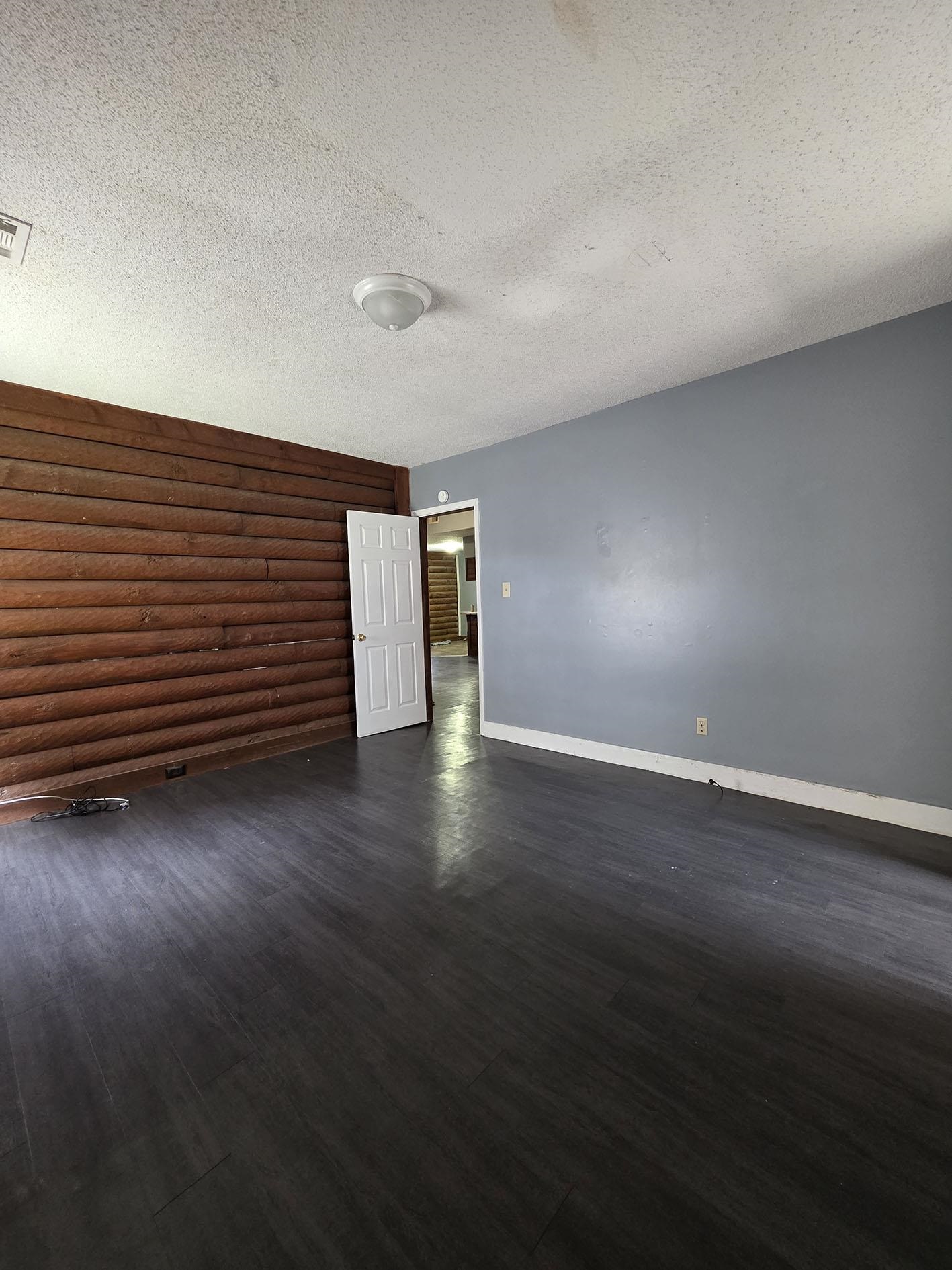 6521 Wimble Road Memphis, TN 38134 - Photo 14 of 18 Spare room featuring a textured ceiling, dark wood-style floors, and rustic walls