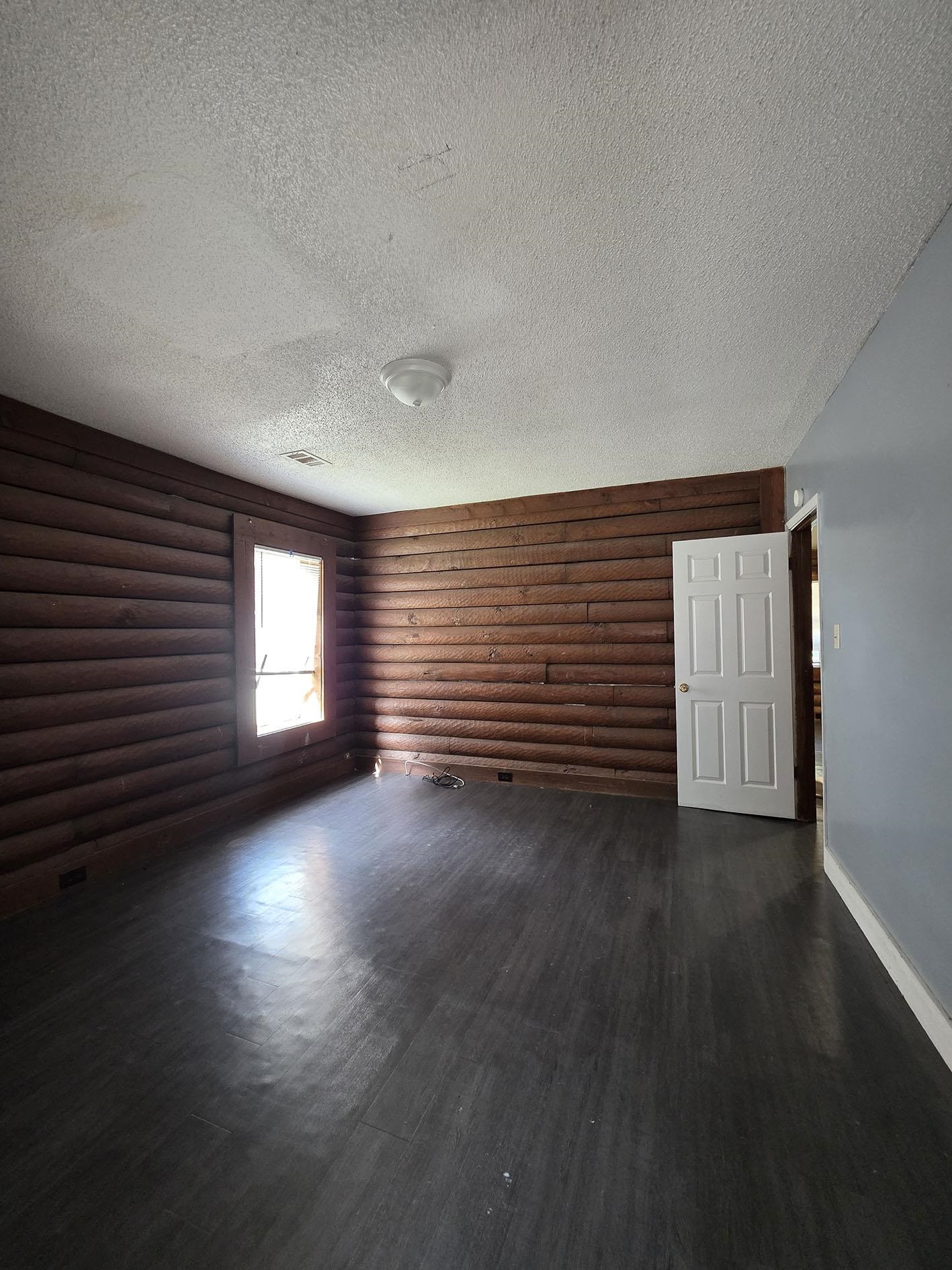 6521 Wimble Road Memphis, TN 38134 - Photo 15 of 18 Unfurnished room with rustic walls, a textured ceiling, and dark wood finished floors