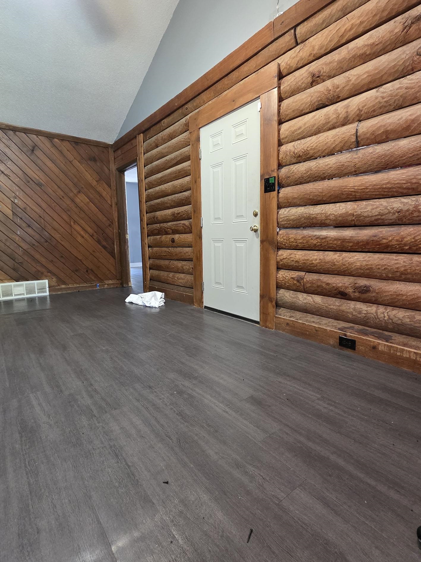 6521 Wimble Road Memphis, TN 38134 - Photo 2 of 18 Unfurnished living room with dark wood finished floors, vaulted ceiling, log walls, and wooden walls