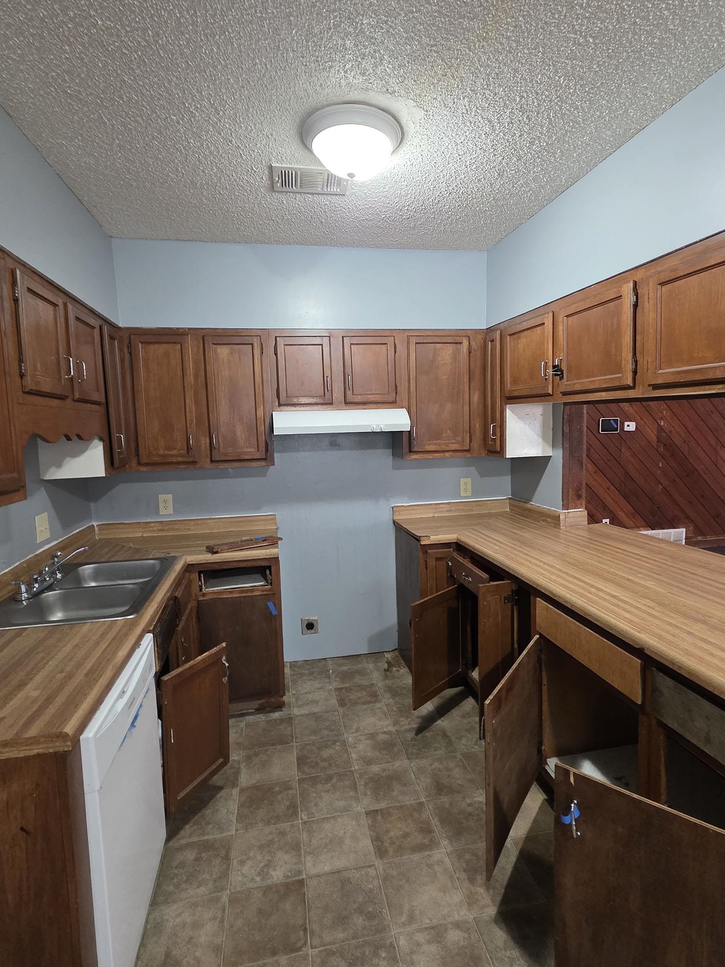 6521 Wimble Road Memphis, TN 38134 - Photo 7 of 18 Kitchen with dishwasher, brown cabinetry, a textured ceiling, light countertops, and a peninsula