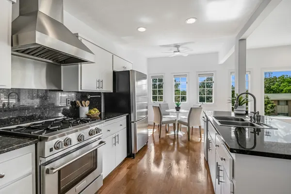 a kitchen with stainless steel appliances a stove a sink a stove cabinets dining table and chairs