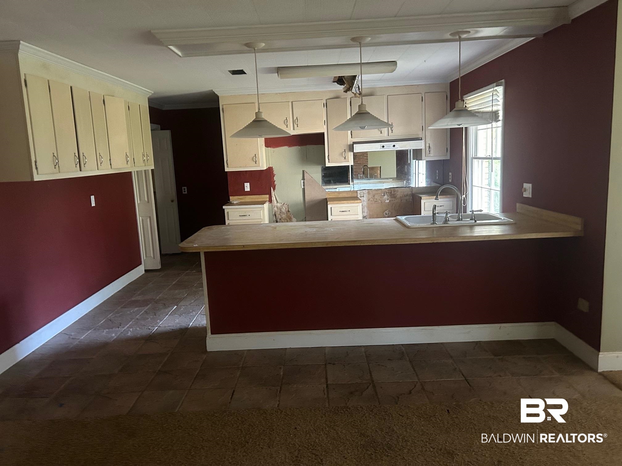 18743 Keller Road Foley, AL 36535 - Photo 2 of 21 Kitchen featuring crown molding, a peninsula, decorative light fixtures, light countertops, and cream cabinetry