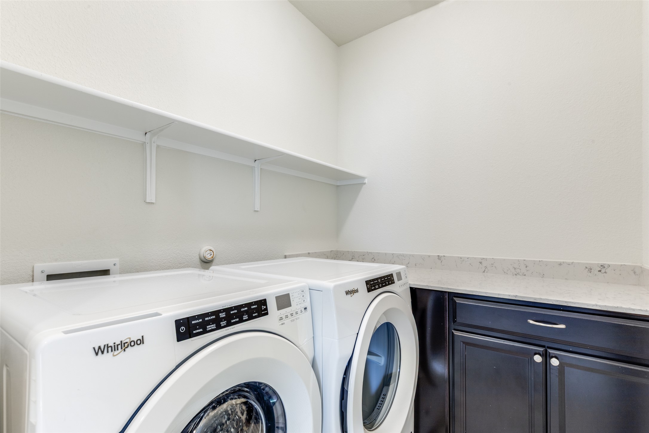 3208 Maysillee Street Austin, TX 78728 - Photo 17 of 23 Laundry area with washing machine and clothes dryer, dark cabinetry and storage