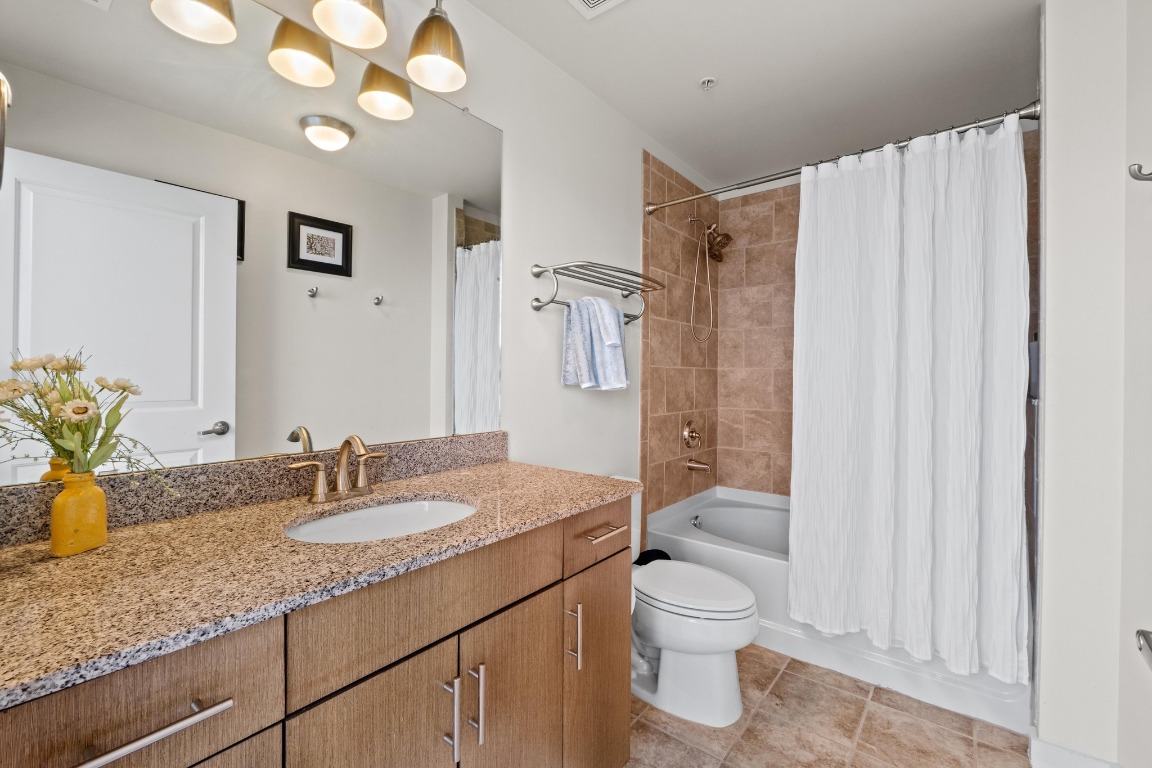 360 Nueces Street, Unit 2808 Austin, TX 78701 - Photo 16 of 29 a bathroom with a granite countertop sink toilet a large mirror a shower and vanity