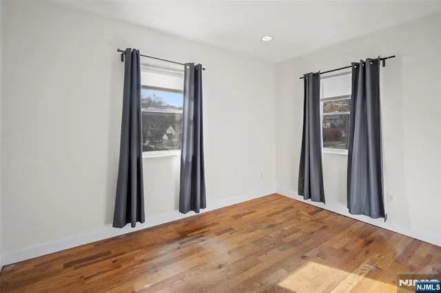 a view of a hallway with wooden floor and a bathroom
