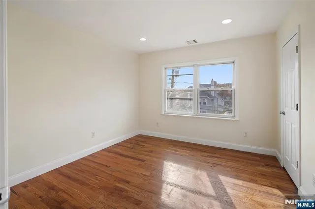 an empty room with wooden floor and window