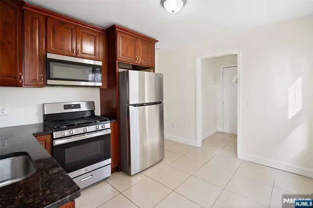 a kitchen with granite countertop a refrigerator and a stove top oven