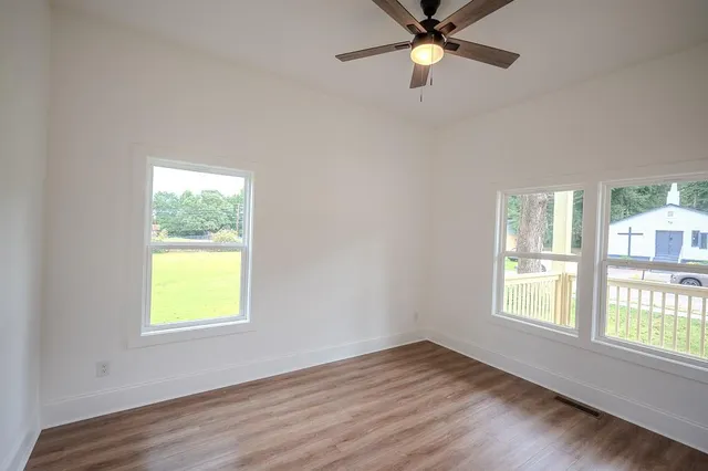 a view of an empty room with window and wooden floor
