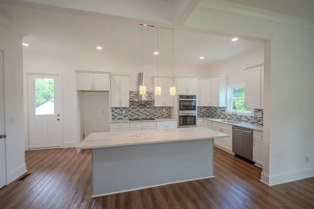 a large kitchen with stainless steel appliances a large counter top a stove and a wooden floors