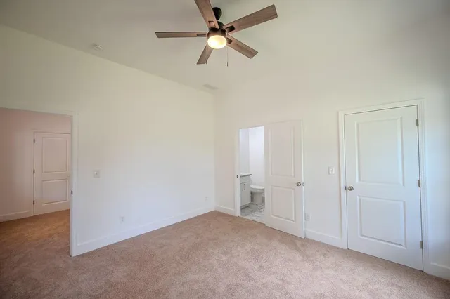 an empty room with closet and a ceiling fan