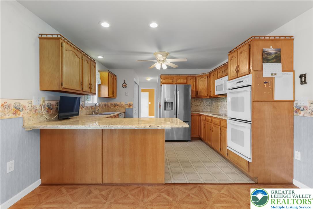 540 Bauer Road Bath, PA 18014 - Photo 15 of 50 a kitchen with stainless steel appliances granite countertop a refrigerator a sink dishwasher and white cabinets with wooden floor